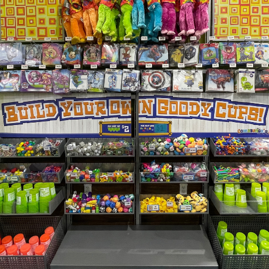 A store interior showcasing a vibrant display of various colorful stuffed animals on top and a build your own goody cup station on the bottom