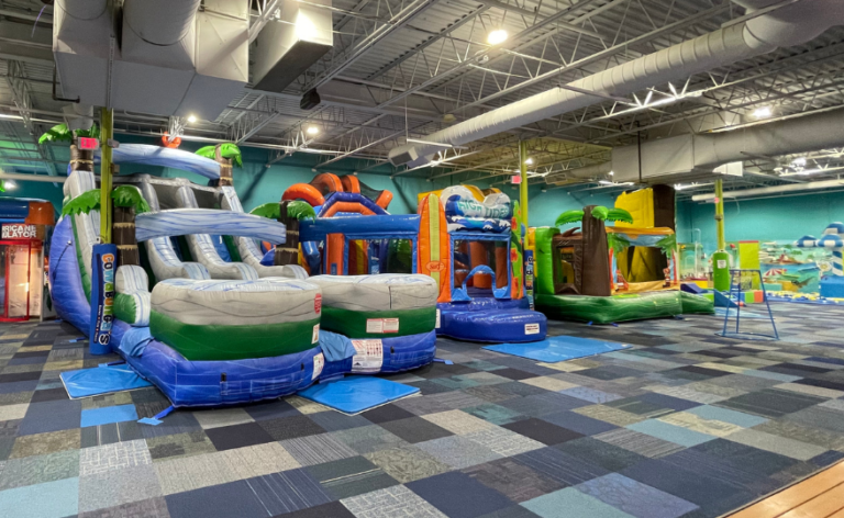 A spacious indoor play area featuring multiple colorful inflatable slides and climbing structures for children to enjoy.