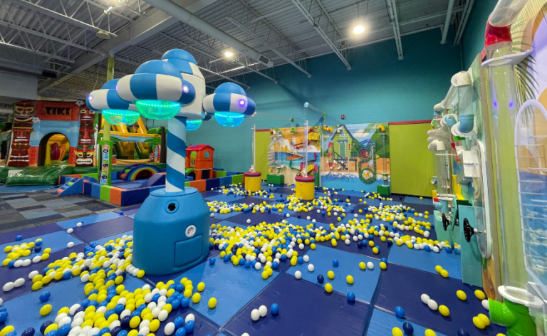 A colorful play area filled with balls and ball walls scattered across a soft surface for children to enjoy