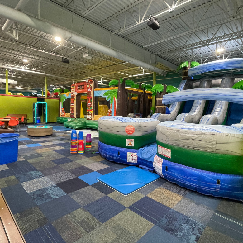 Colorful and inviting private party gym with two themed inflatables and a projection play floor