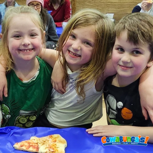 Three friends smiling together at a Cowabunga’s birthday party in Manchester, NH