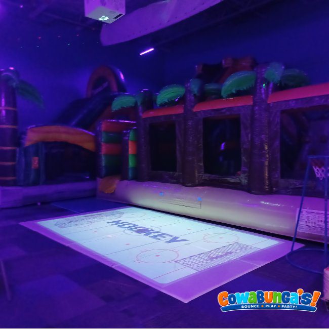Purple-lit play gym with an interactive floor at Cowabunga’s Manchester, NH
