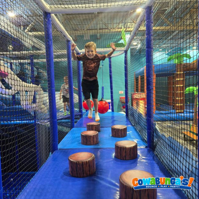 Child exploring a netted play structure at Cowabunga’s Manchester, NH