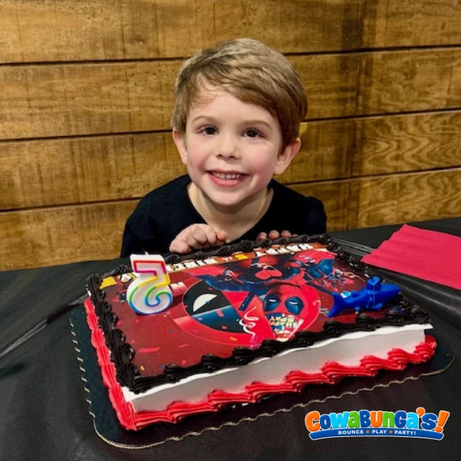 Birthday child smiling behind a decorated cake at Cowabunga’s in North Reading, MA