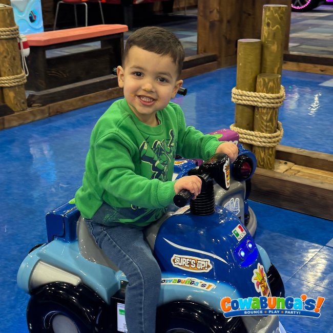 Child riding a small play vehicle at Cowabunga’s North Reading, MA