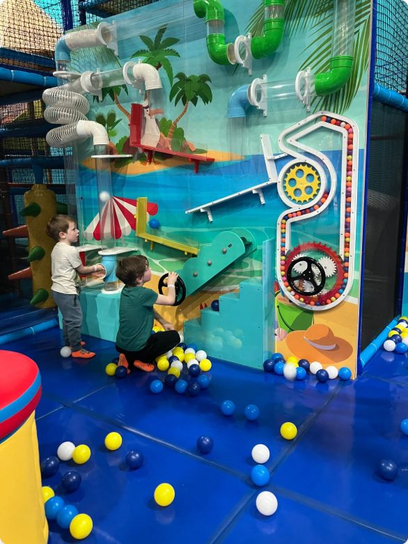 Children turning gears and exploring the ball wall at Cowabunga’s